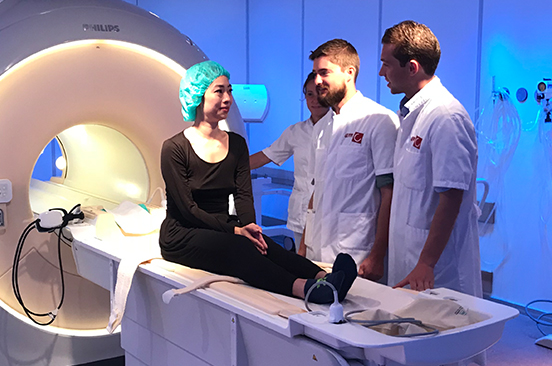 Onderzoekers Matthias Cabri en Onno Baur (r) overleggen met Ani Liu kort voordat ze de MRI in gaat.