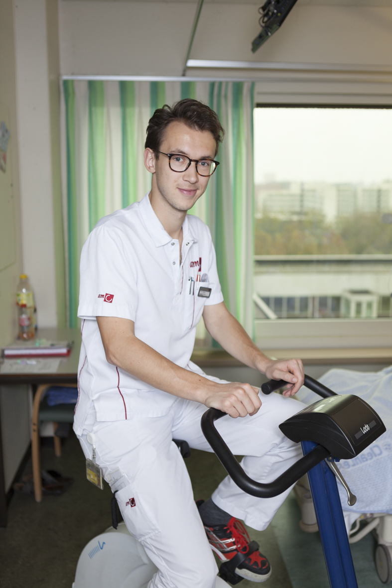Fysiotherapeut Sven Geelen demonstreert een hometrainer op de kamer van een patiënt.